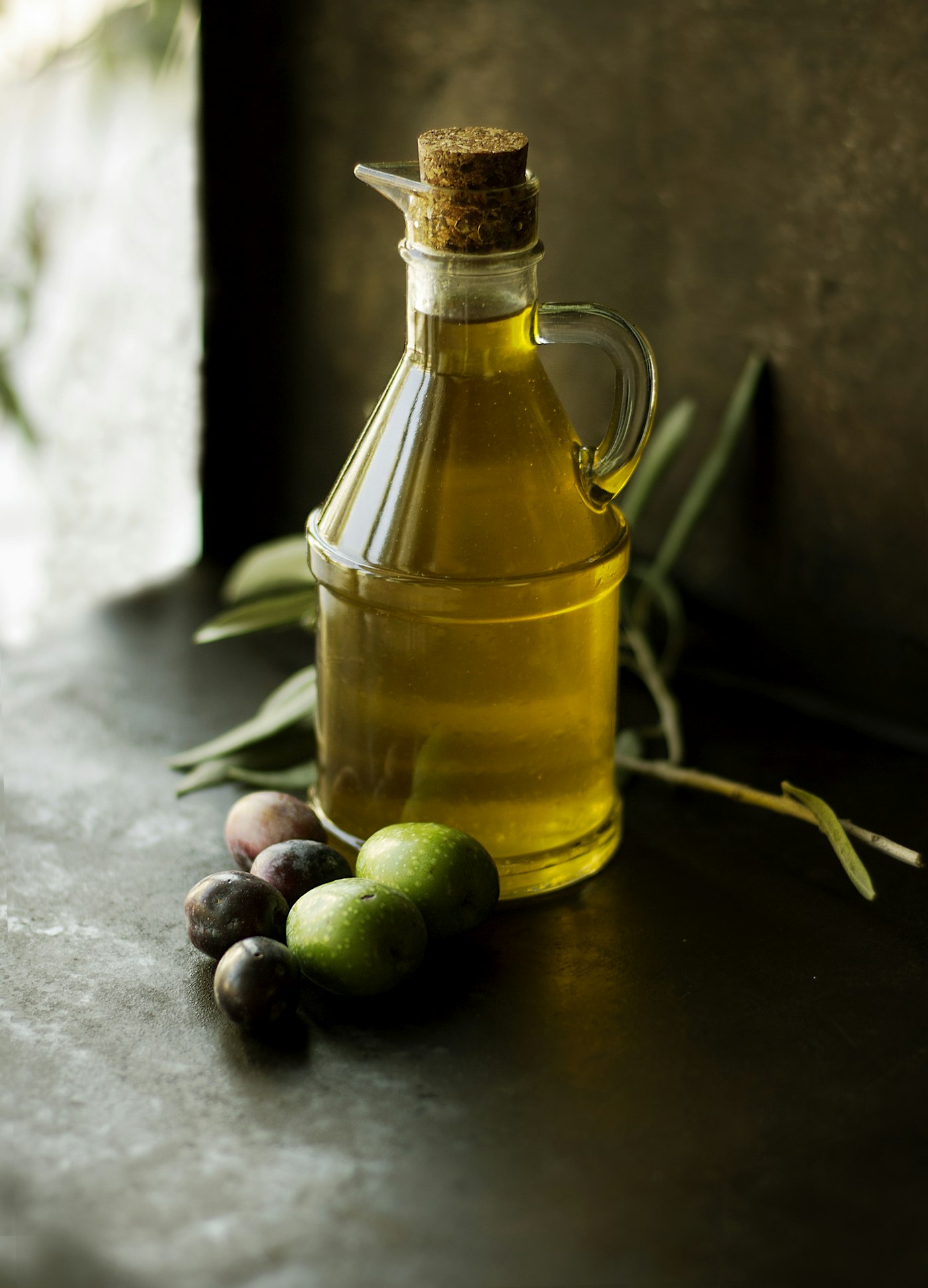 Extra virgin olive oil in a glass bottle with olives
